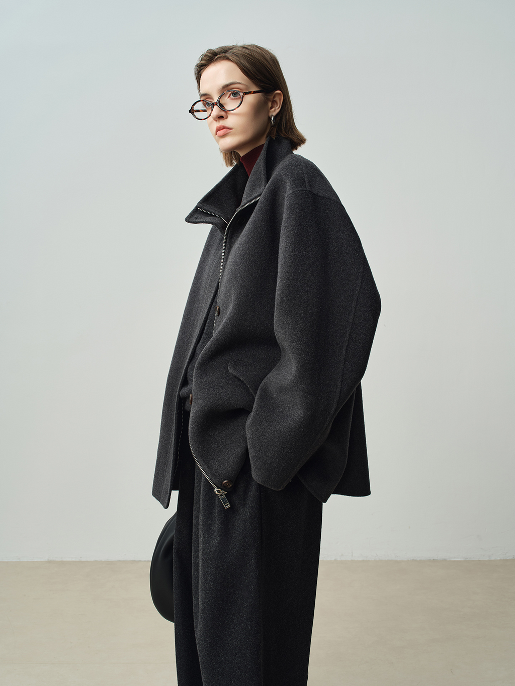 A stylish women’s winter coat with a zipper on both sides, featuring a stand-up collar and a short length; made of wool.