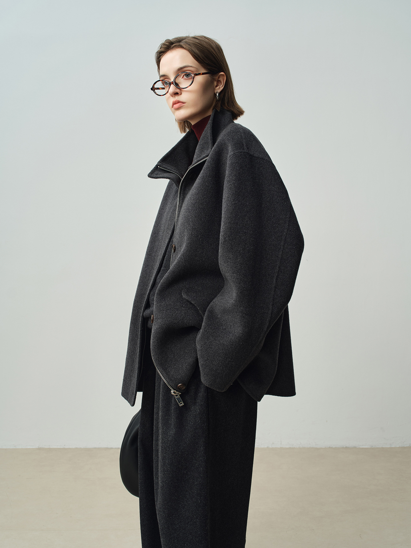 A stylish women’s winter coat with a zipper on both sides, featuring a stand-up collar and a short length; made of wool.