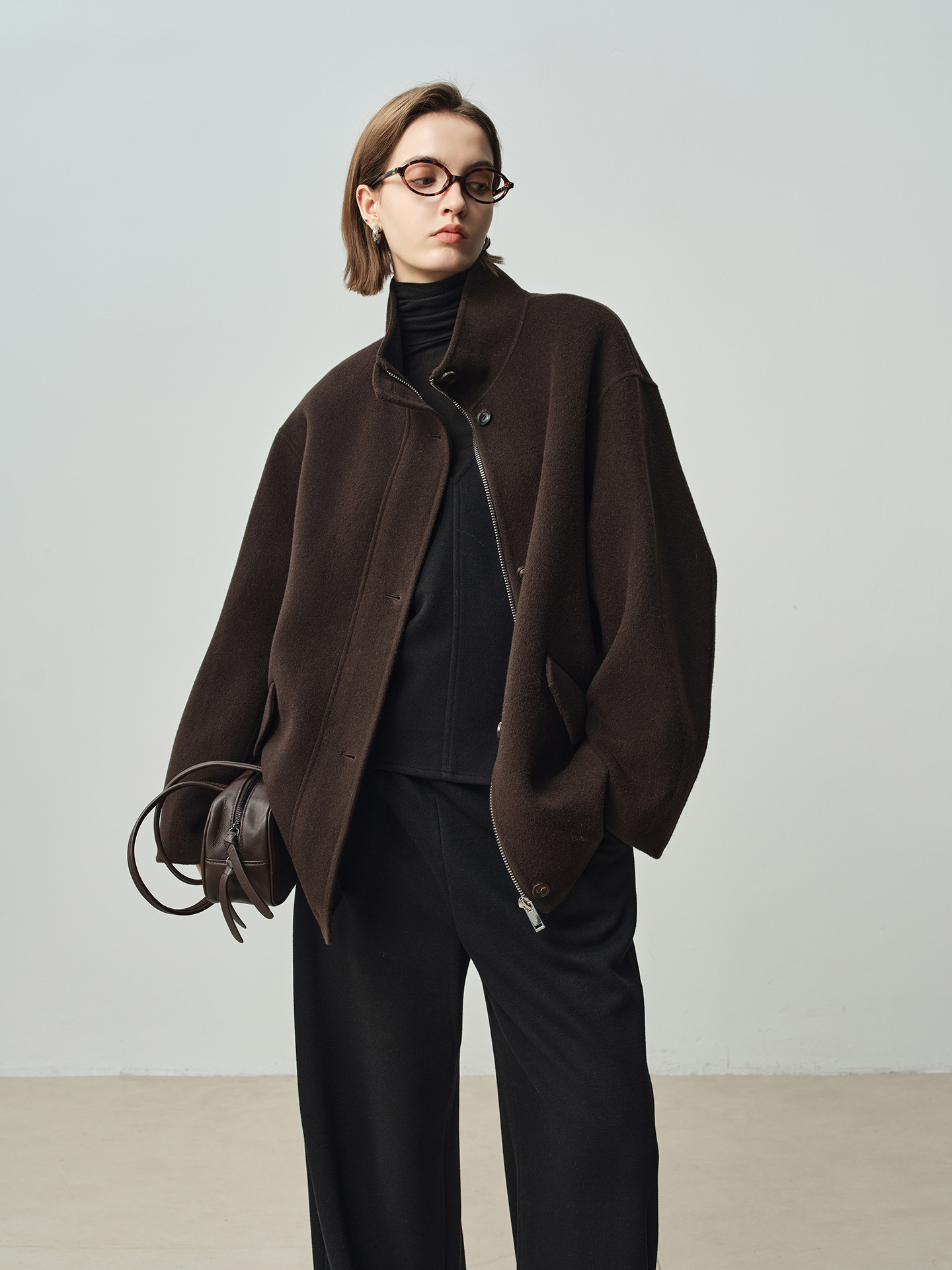 A stylish women’s winter coat with a zipper on both sides, featuring a stand-up collar and a short length; made of wool.