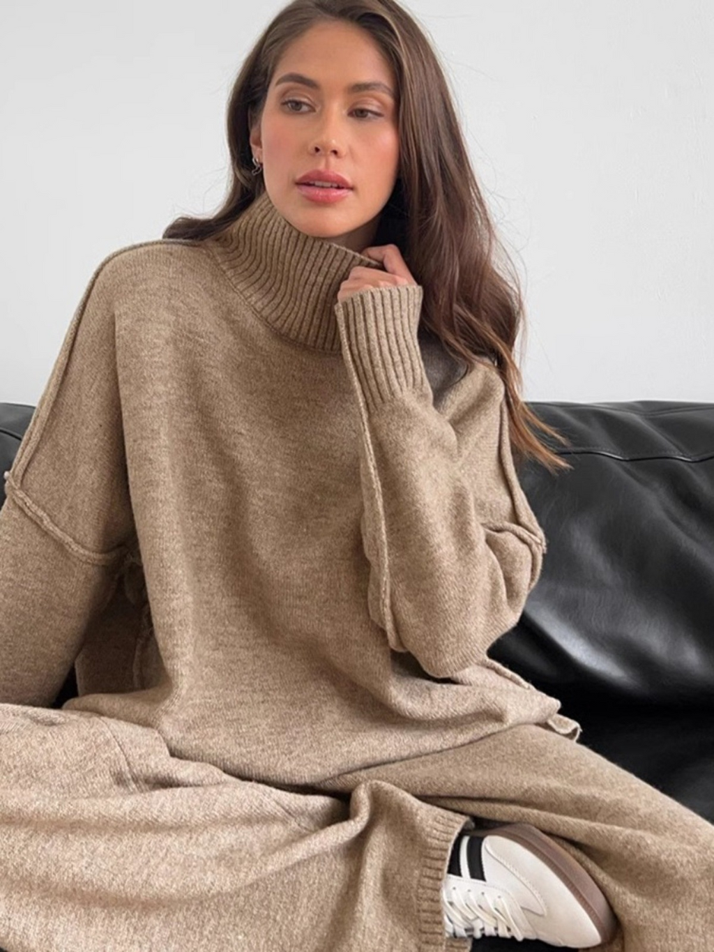 Women’s knitted set consisting of a thick, loose sweater with high collar and wide-leg pants – a two-piece outfit.