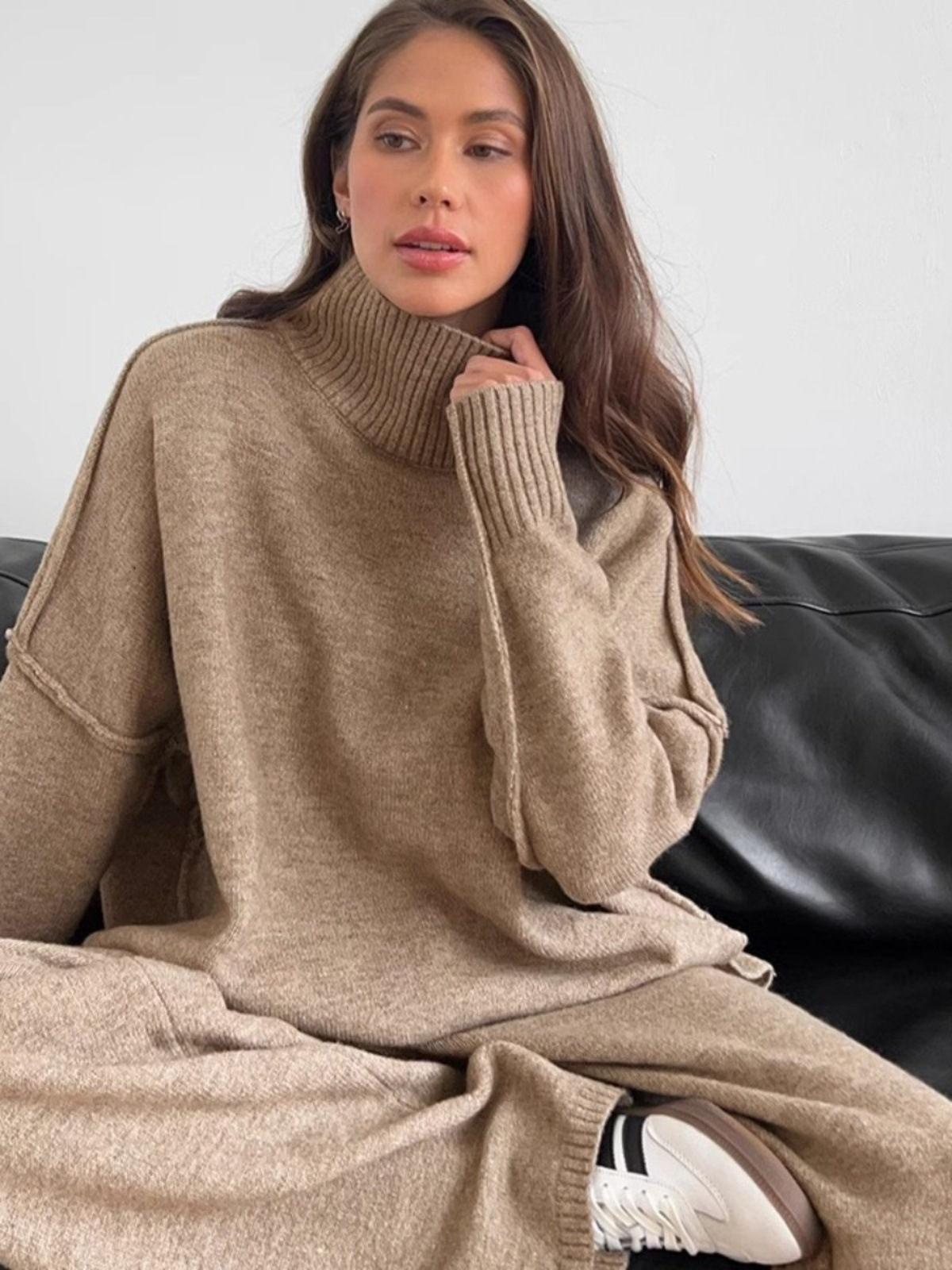 Women’s knitted set consisting of a thick, loose sweater with high collar and wide-leg pants – a two-piece outfit.
