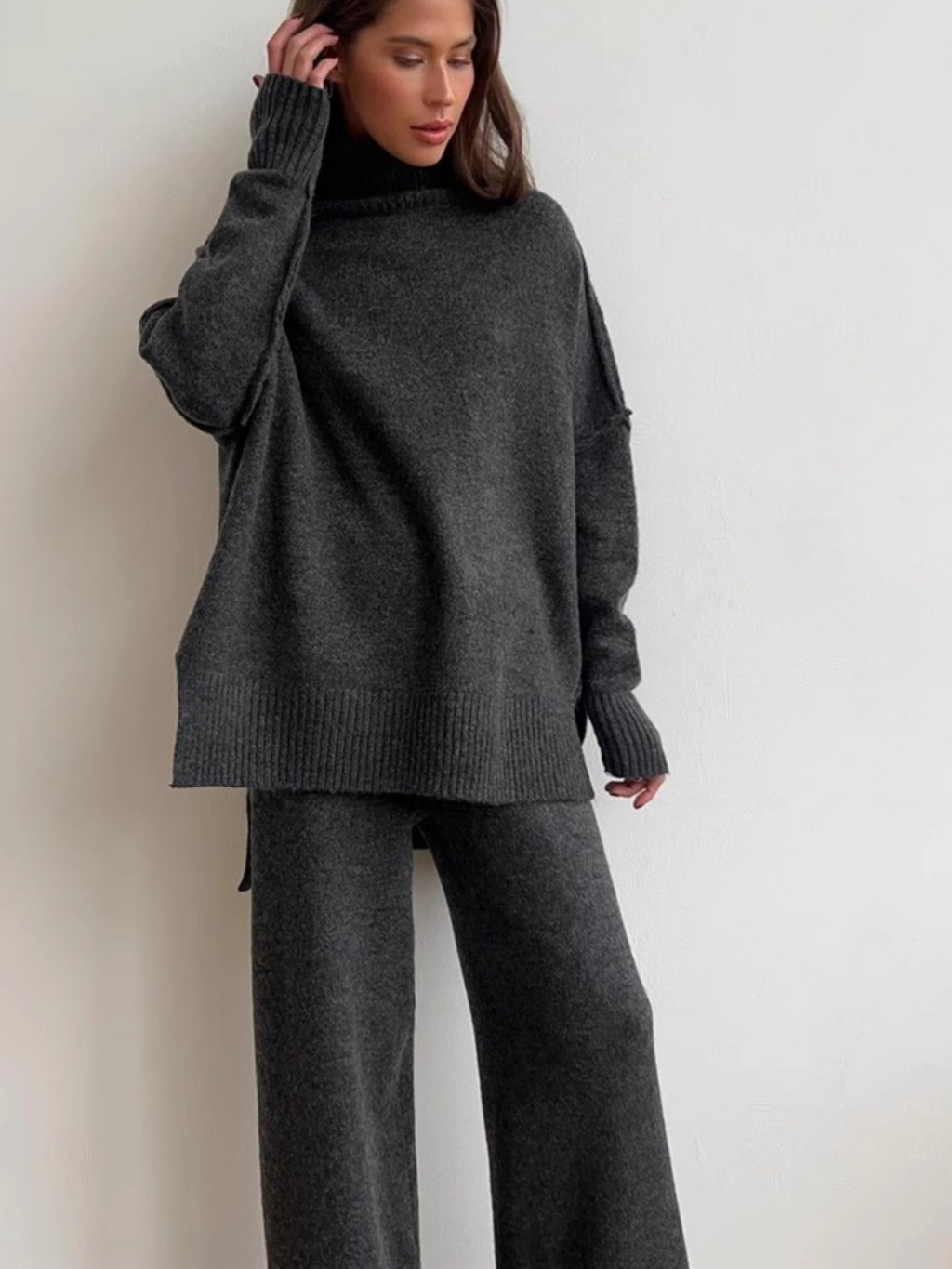 Women’s knitted set consisting of a thick, loose sweater with high collar and wide-leg pants – a two-piece outfit.