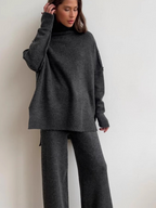 Women’s knitted set consisting of a thick, loose sweater with high collar and wide-leg pants – a two-piece outfit.