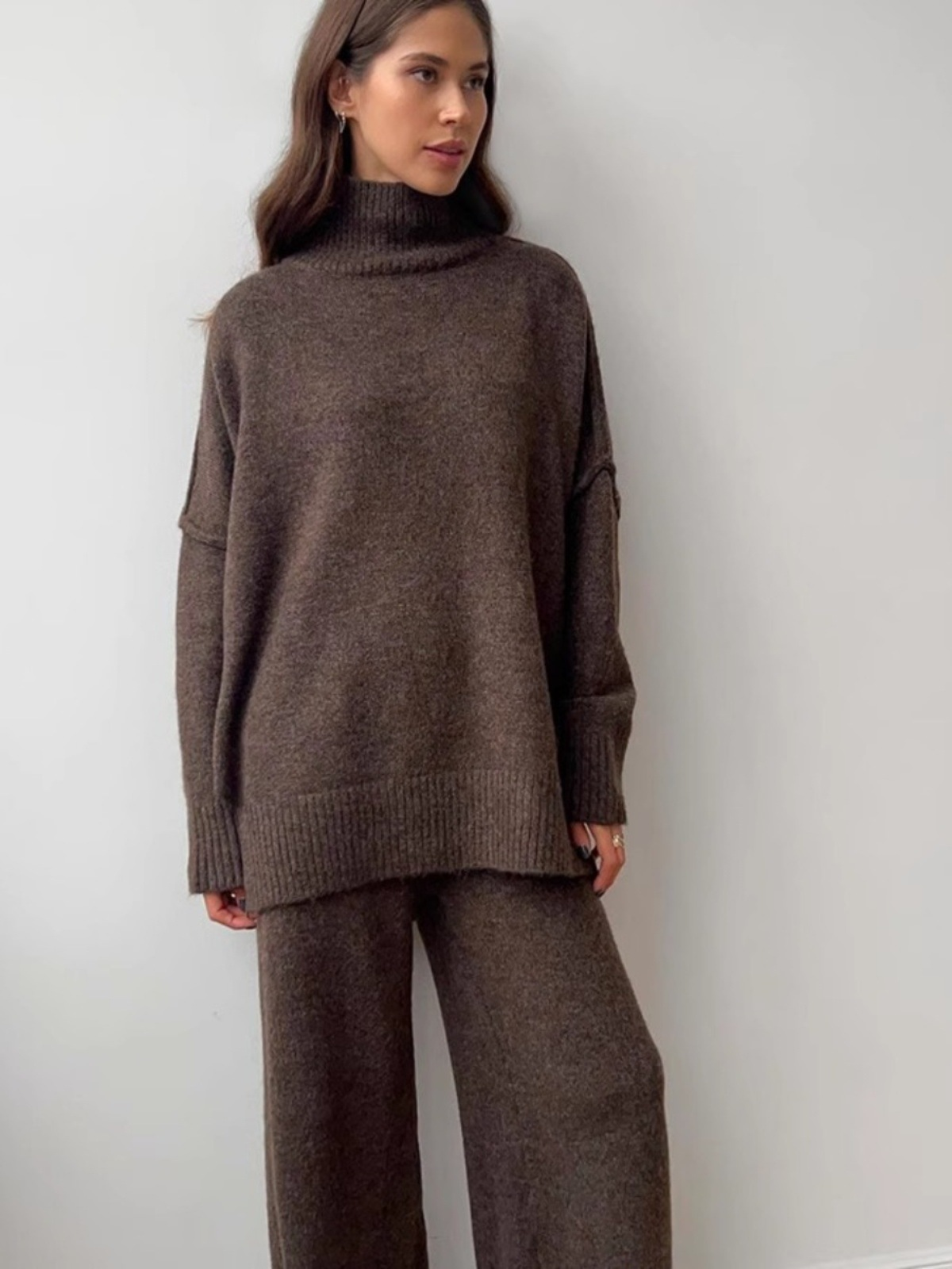 Women’s knitted set consisting of a thick, loose sweater with high collar and wide-leg pants – a two-piece outfit.