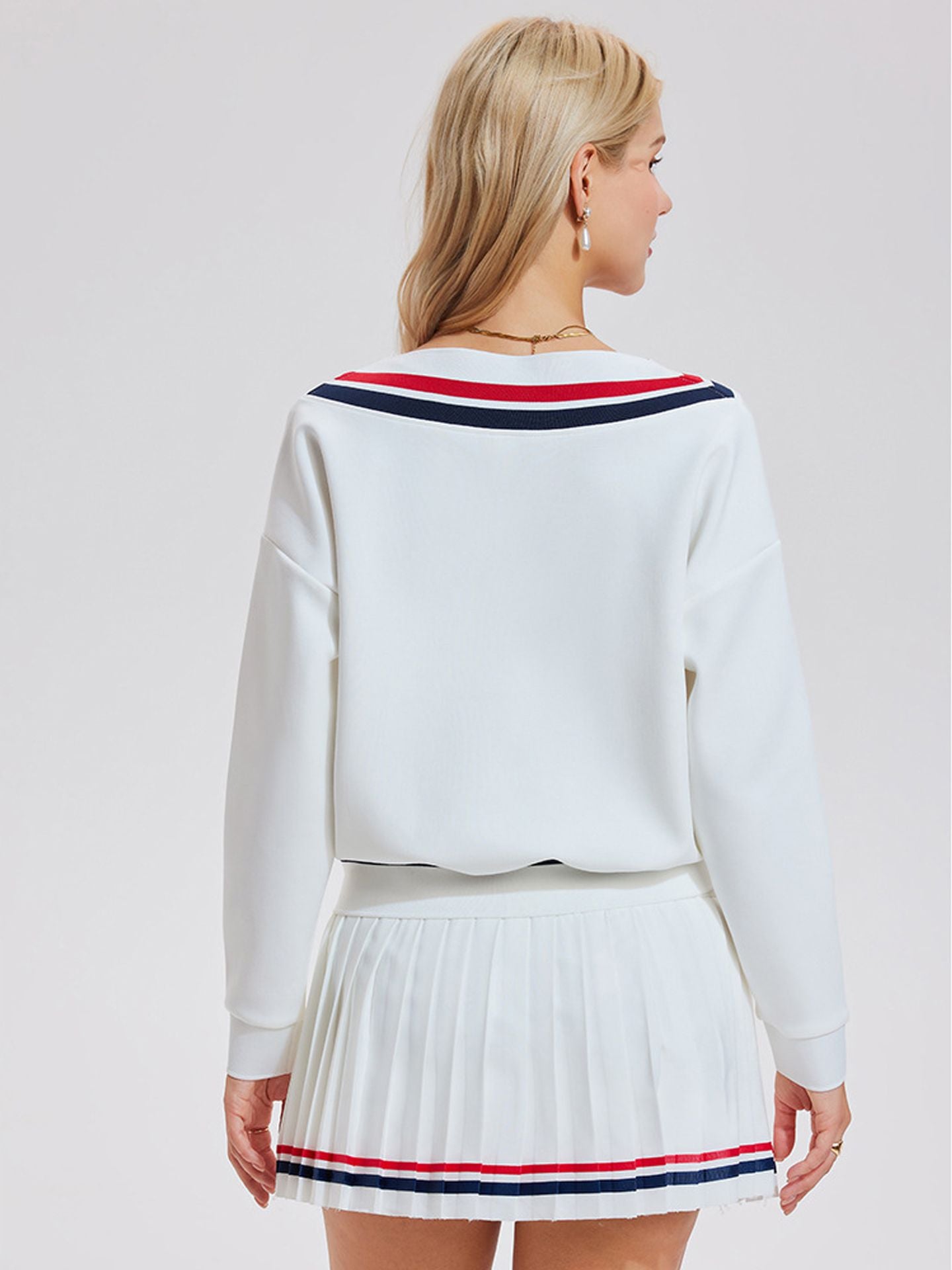 Long-sleeved sports top for women, designed for tennis play. Features a large V-neck and a stylish, casual design.